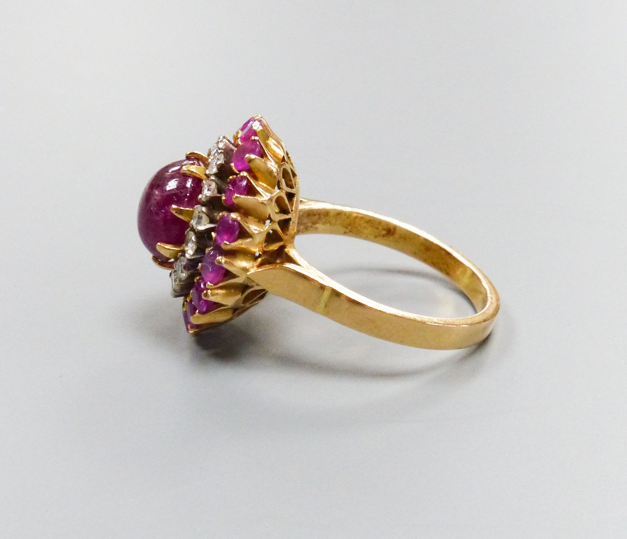 An Indian yellow metal, cabochon ruby and diamond cluster ring, size N, gross weight 8.3 grams, (central stone cracked).